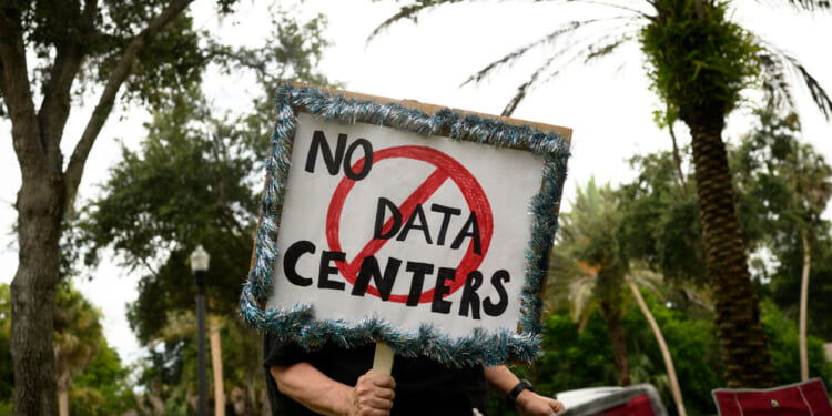 A person holds signs during a nationwide protest against AI data center expansion outside Peace Hall in New Port Richey, Florida on July 18, 2026. (Photo by Thomas Simonetti / AFP via Getty Images)