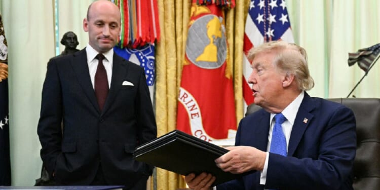 President Donald Trump holds binders containing two executive orders he signed Thursday targeting birthright citizenship for some individuals and "birth tourism." With him is White House Deputy Chief of Staff Stephen Miller.