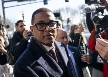 Former CNN host Don Lemon is unlikely to succeed in his motion to dismiss the case for vindictive prosecution, Josh Hammer says. Pictured: Don Lemon, a man in glasses and a dark coat walks outside, surrounded by reporters, cameras, and microphones, with people and trees in the background.