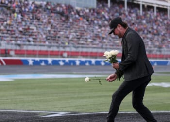 NASCAR Hall of Famer Kurt Busch lays white roses on the "8" stenciled of the infield grass during the remembrance ceremony for his brother, Kyle Busch, who passed away suddenly at the age of 41, prior to the NASCAR Cup Series Coca-Cola 600 at Charlotte Motor Speedway on May 24, 2026, in Concord, North Carolina.