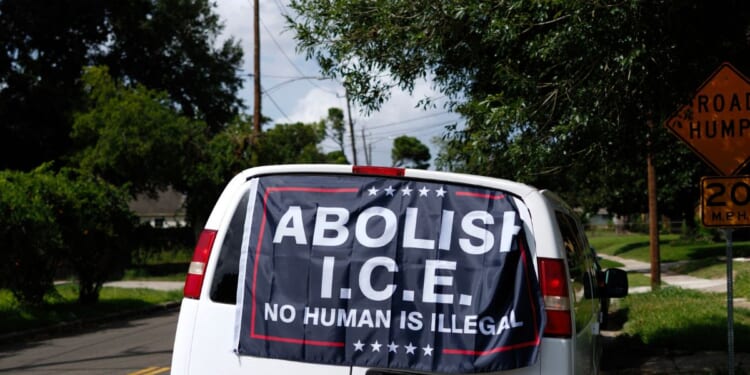 A banner reading "Abolish ICE, No Human is Illegal" is displayed on a van in Houston, Texas.