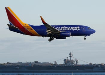A Southwest Airlines Boeing 737 airplane approaches San Diego International Airport for a landing after a flight from San Antonio with the USS Carl Vinson in the background on June 20, 2026, in San Diego, California.