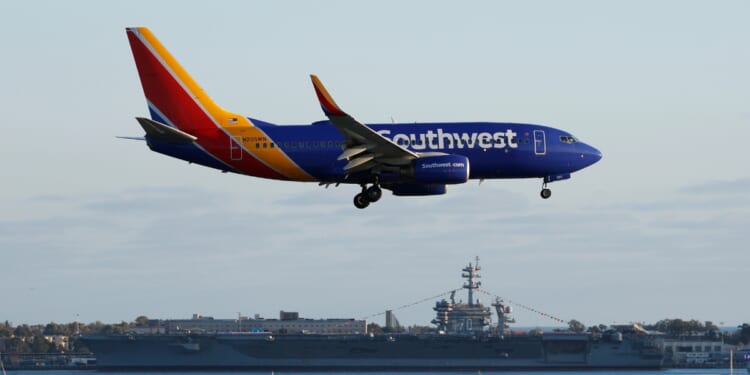 A Southwest Airlines Boeing 737 airplane approaches San Diego International Airport for a landing after a flight from San Antonio with the USS Carl Vinson in the background on June 20, 2026, in San Diego, California.