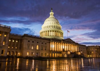 The Capitol Building stands on a dark night illuminated by interior lights.