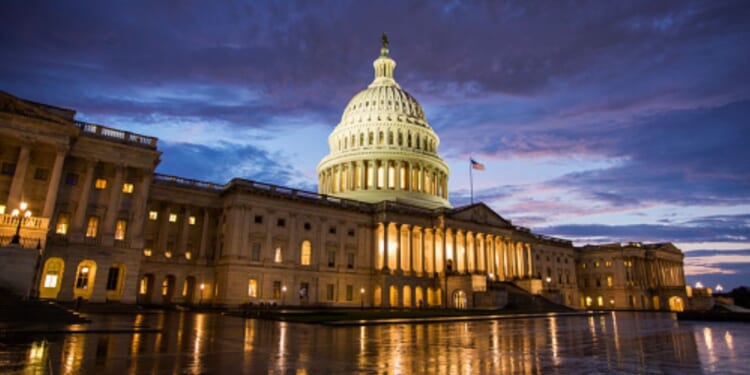 The Capitol Building stands on a dark night illuminated by interior lights.