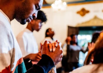 A young man prays with others during a church service.
