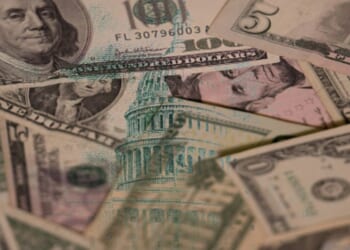 Dollar bills are pictured with an overlay of the United States Capitol Building.
