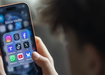 A young boy holds an iPhone and views various apps.