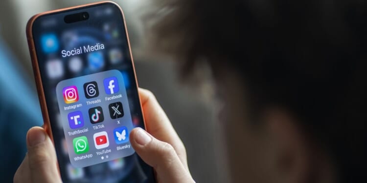 A young boy holds an iPhone and views various apps.
