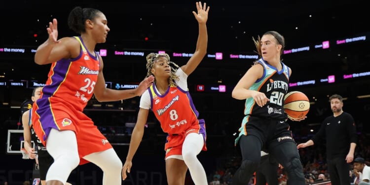 Sabrina Ionescu of the New York Liberty handles the ball against Alyssa Thomas and Monique Akoa Makani of the Phoenix Mercury during the first half of the WNBA game at Mortgage Matchup Center on Aug. 1, 2026, in Phoenix, Arizona.