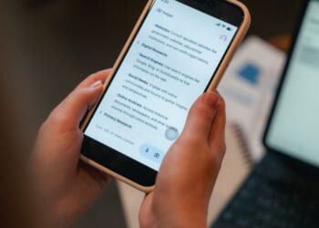 A woman looks at a phone screen with an AI user interface displayed on it.