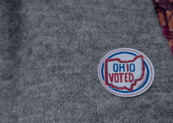 A round sticker reading OHIO VOTED with an outline of Ohio is on a gray sweater.