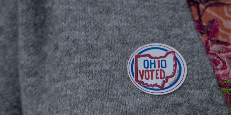 A round sticker reading OHIO VOTED with an outline of Ohio is on a gray sweater.