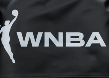 A white logo for the WNBA is displayed on a piece of black fabric.