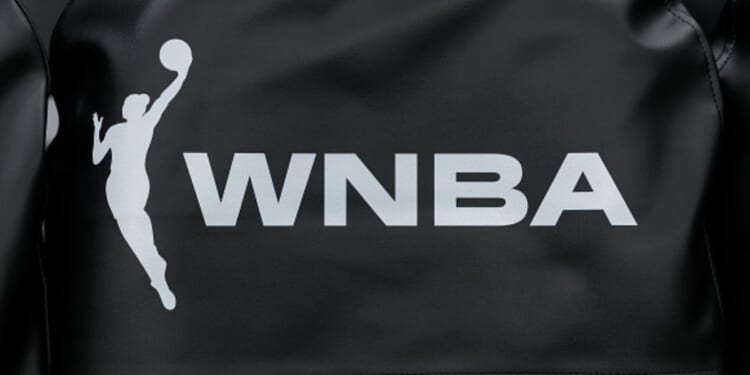 A white logo for the WNBA is displayed on a piece of black fabric.