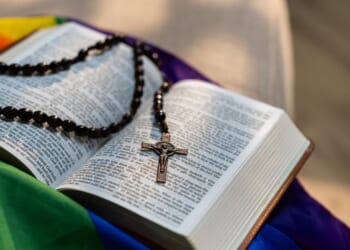 A Holy Bible sitting on top of a rainbow flag.