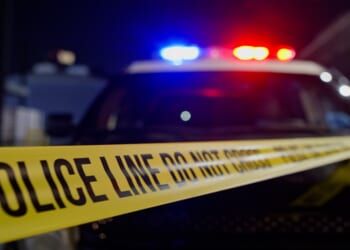 Police lights flash above crime scene tape in a stock photo.