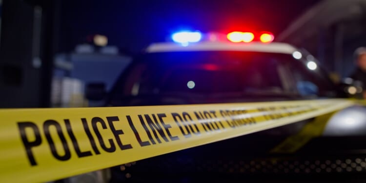 Police lights flash above crime scene tape in a stock photo.