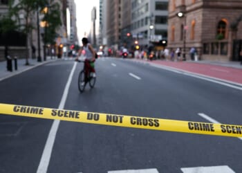 A cyclist is seen behind crime scene tape as police respond to a shooting incident in the Midtown Manhattan neighborhood of New York on July 28, 2025.