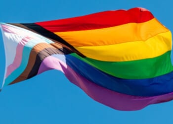 An LGBTQ flag flies in the sky.