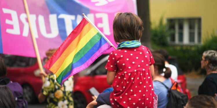 A child sits on her mother's shoulders at an LGBT pride event.