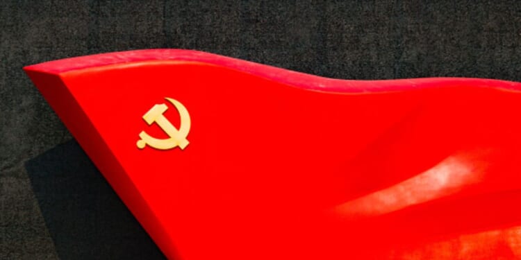 An object depicting a hammer and sickle icon on the edge is pictured ahead of a black surface.