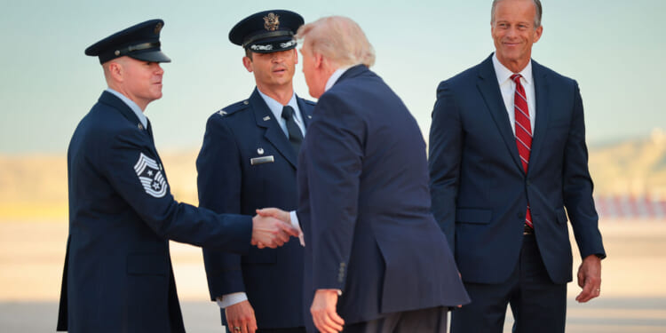 resident Donald Trump is greeted by Senate Majority Leader John Thune (R-SD) (right) on the tarmac after landing in Air Force One.