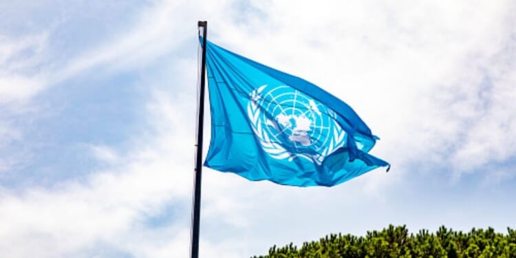 The United Nations flag waves in the sky.