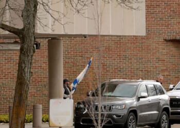 A person carries a flag of Israel from Temple Israel synagogue in West Bloomfield, Michigan, on March 13, 2026, after a person drove a vehicle into the synagogue a day earlier.