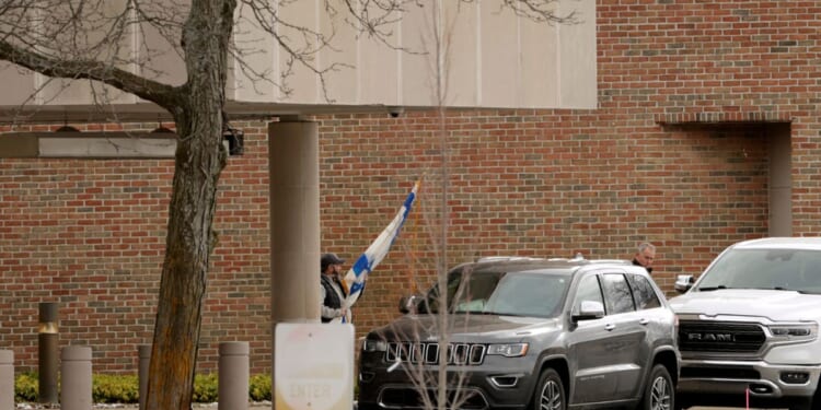 A person carries a flag of Israel from Temple Israel synagogue in West Bloomfield, Michigan, on March 13, 2026, after a person drove a vehicle into the synagogue a day earlier.