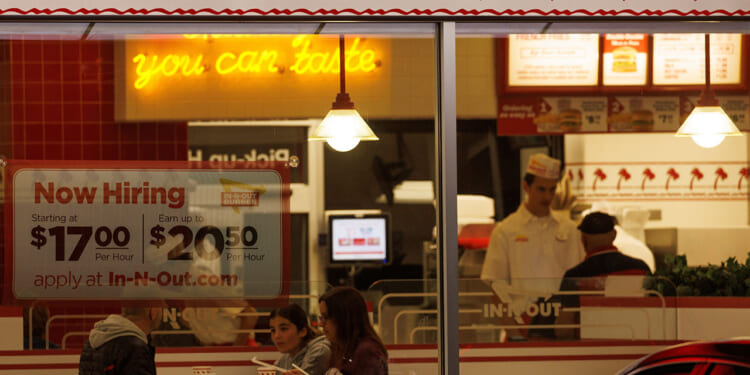 A "Now hiring" sign is displayed on the window of a fast food restaurant in Encinitas, California, May 9, 2022. REUTERS/Mike Blake/File Photo