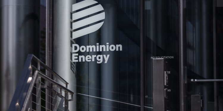 The Dominion Energy logo and name are displayed on the glass entrance of a modern building, with reflections and metal railings visible nearby.