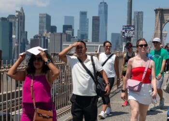 People walk across the Brooklyn Bridge on a day where the heat index is expected to top 100 degrees on July 25, 2025, in the Brooklyn borough of New York City.