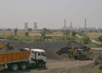 An excavator loads coal sand into a transport truck near a thermal power plant in a coal yard, in an industrial area on April 21, 2026, in the outskirts of New Delhi, India.
