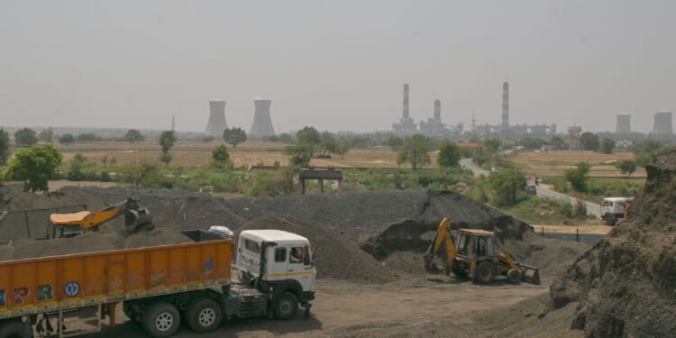 An excavator loads coal sand into a transport truck near a thermal power plant in a coal yard, in an industrial area on April 21, 2026, in the outskirts of New Delhi, India.