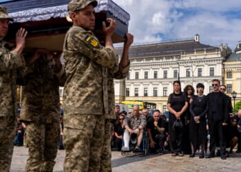 A pregnant soldier mourns her 21-year-old husband at his funeral in Ukraine