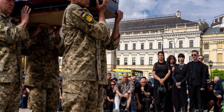 A pregnant soldier mourns her 21-year-old husband at his funeral in Ukraine