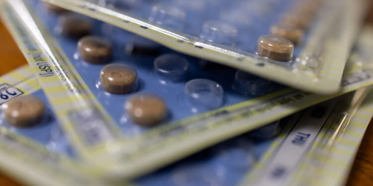 Close-up of several overlapping blister packs with round brown tablets inside, some tablets removed, on a wooden surface.