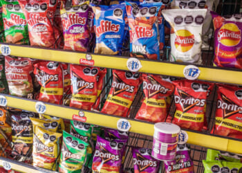 Shelves stocked with assorted bags of Mexican chips, including Ruffles, Sabritas, and Doritos, in various colorful packaging, with some Pringles cans at the bottom.