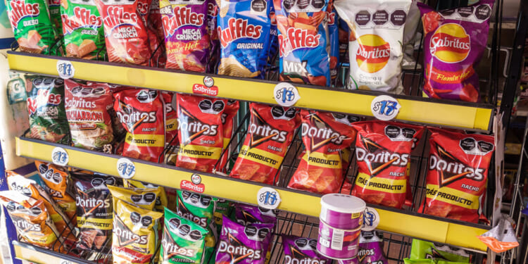 Shelves stocked with assorted bags of Mexican chips, including Ruffles, Sabritas, and Doritos, in various colorful packaging, with some Pringles cans at the bottom.