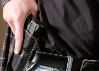 A man drawing a gun out of a leather holster.