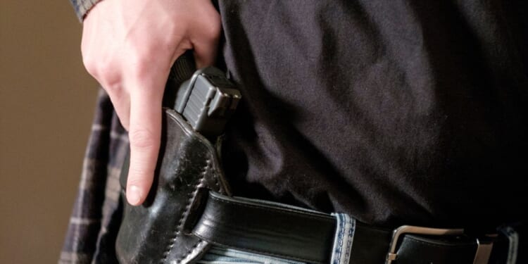 A man drawing a gun out of a leather holster.