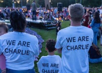 People wear t-shirts reading "We Are Charlie" as they pay their respects during a candlelight vigil for right-wing activist Charlie Kirk at a makeshift memorial at Memorial Park in Provo, Utah, on Sept. 12, 2025, after he was shot during a public event at Utah Valley University.