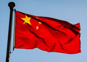 The Chinese flag flies in the blue sky.