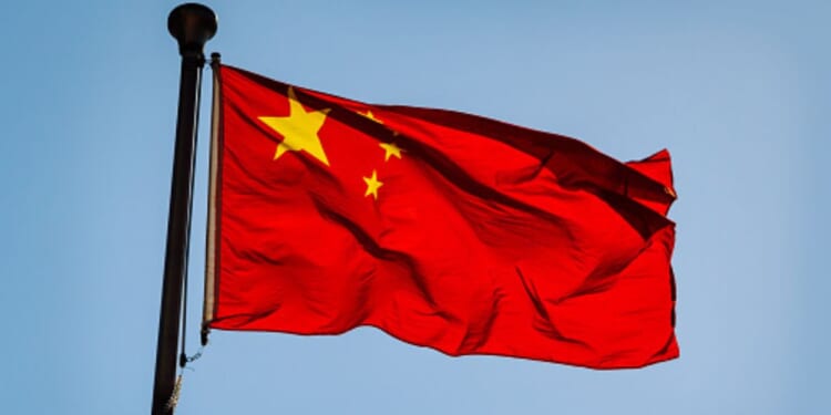 The Chinese flag flies in the blue sky.