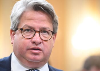 Gabe Sterling, Director of Special Projects for Secretary of State Brad Raffensperger, appears with glasses, wearing a dark suit and tie. He speaks indoors with a blurred background and bright lighting.