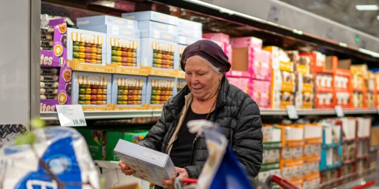A woman checks a box of cookies while shopping at a Costco Wholesale store on April 13, 2024, in Colchester, Vermont.