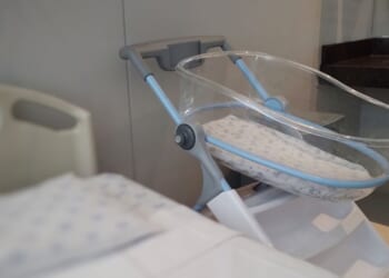 An acrylic crib for a newborn in a maternity room.