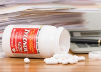 A Tylenol bottle is flipped over with pills pouring out.
