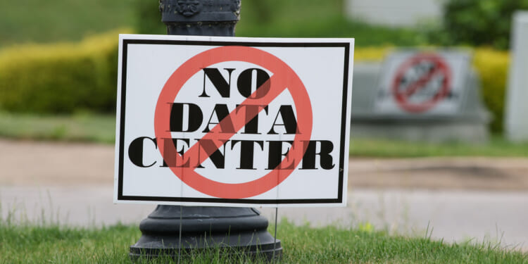 A sign on grass reads "NO DATA CENTER" with a red circle and slash, indicating opposition to a data center.